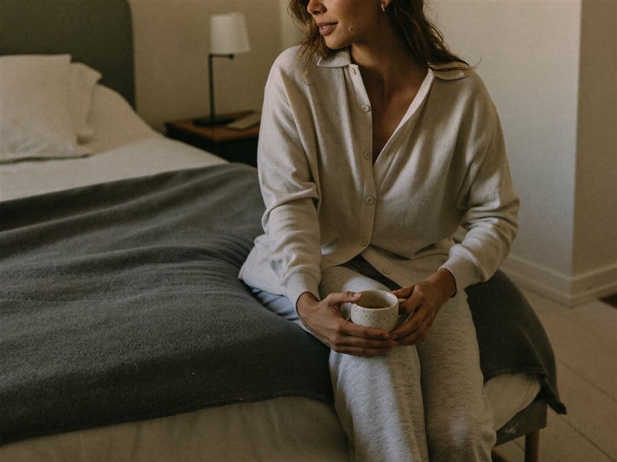 A mother sitting on her bed with a warm cup of tea