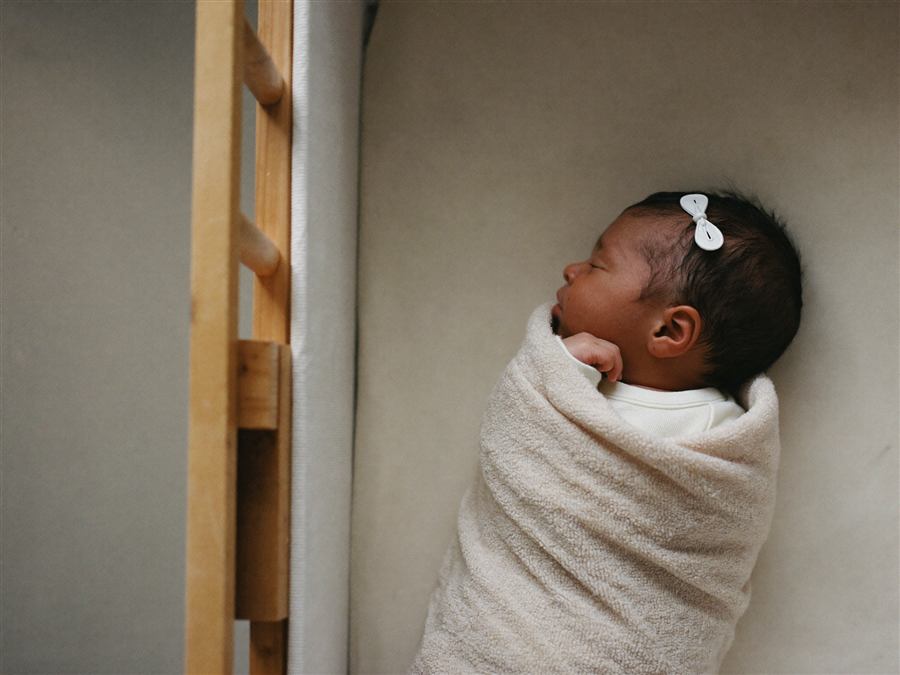 A swaddled newborn sleeping peacefully in a bassinet